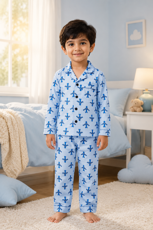 Child wearing blue pajamas with airplane pattern in a bedroom setting