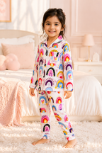 Child wearing colorful rainbow-themed pajamas in a bedroom setting
