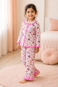 Young girl wearing a floral pajama set with pink accents in a cozy room.