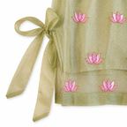 Green fabric with pink floral embroidery and a ribbon on a white background