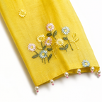 Yellow fabric with floral embroidery and pearl trim on a white background