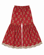 Red floral-patterned pants with lace trim on a white background