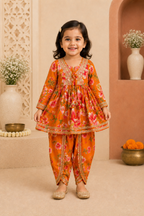 Young girl in a floral traditional outfit standing in a decorated room.