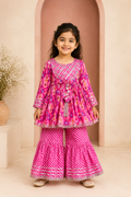 Young girl in a pink traditional outfit standing in front of a beige archway.