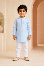 Child wearing a light blue kurta with white pants in an indoor setting