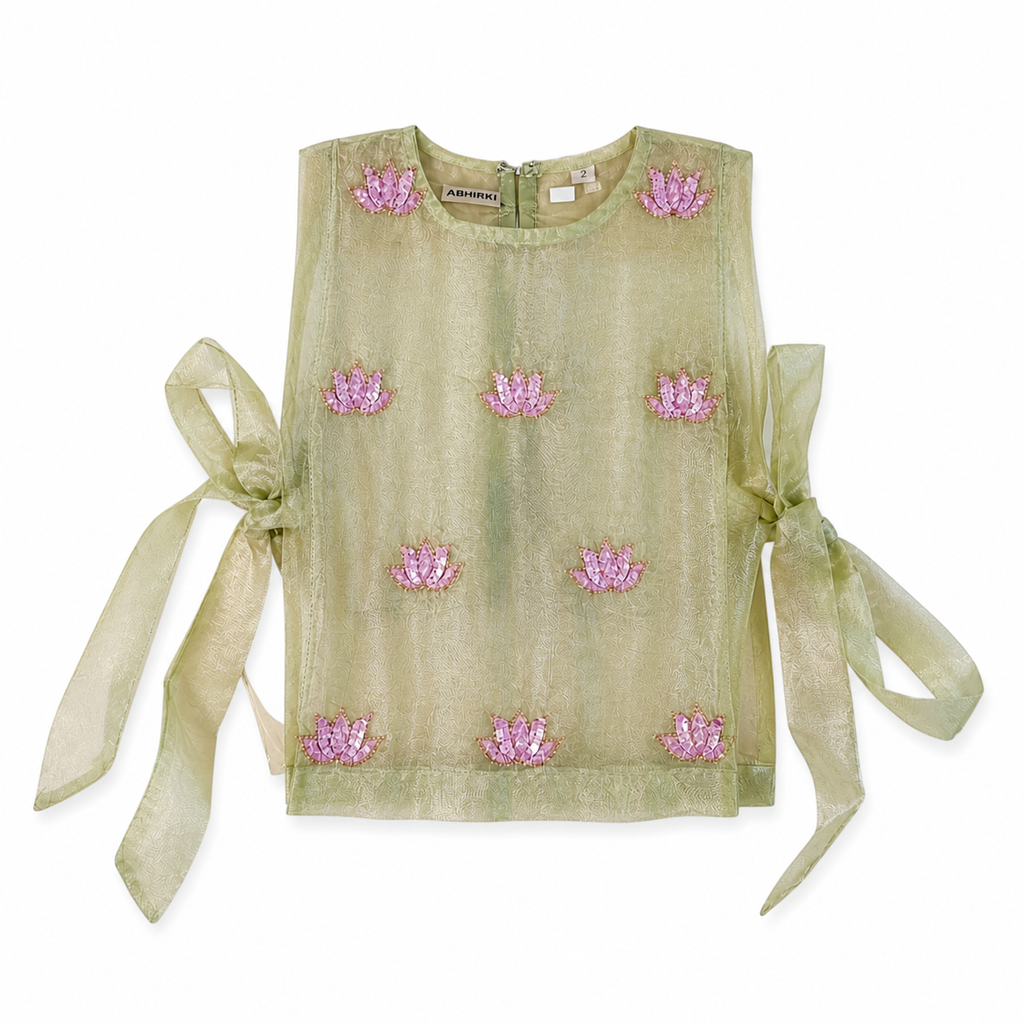 Green top with pink floral embellishments and sheer sleeves on a white background