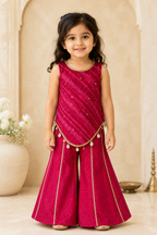 Young girl in a pink traditional outfit standing in a decorated room.