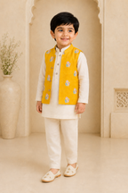 Child wearing a traditional outfit with a yellow vest in an elegant interior setting