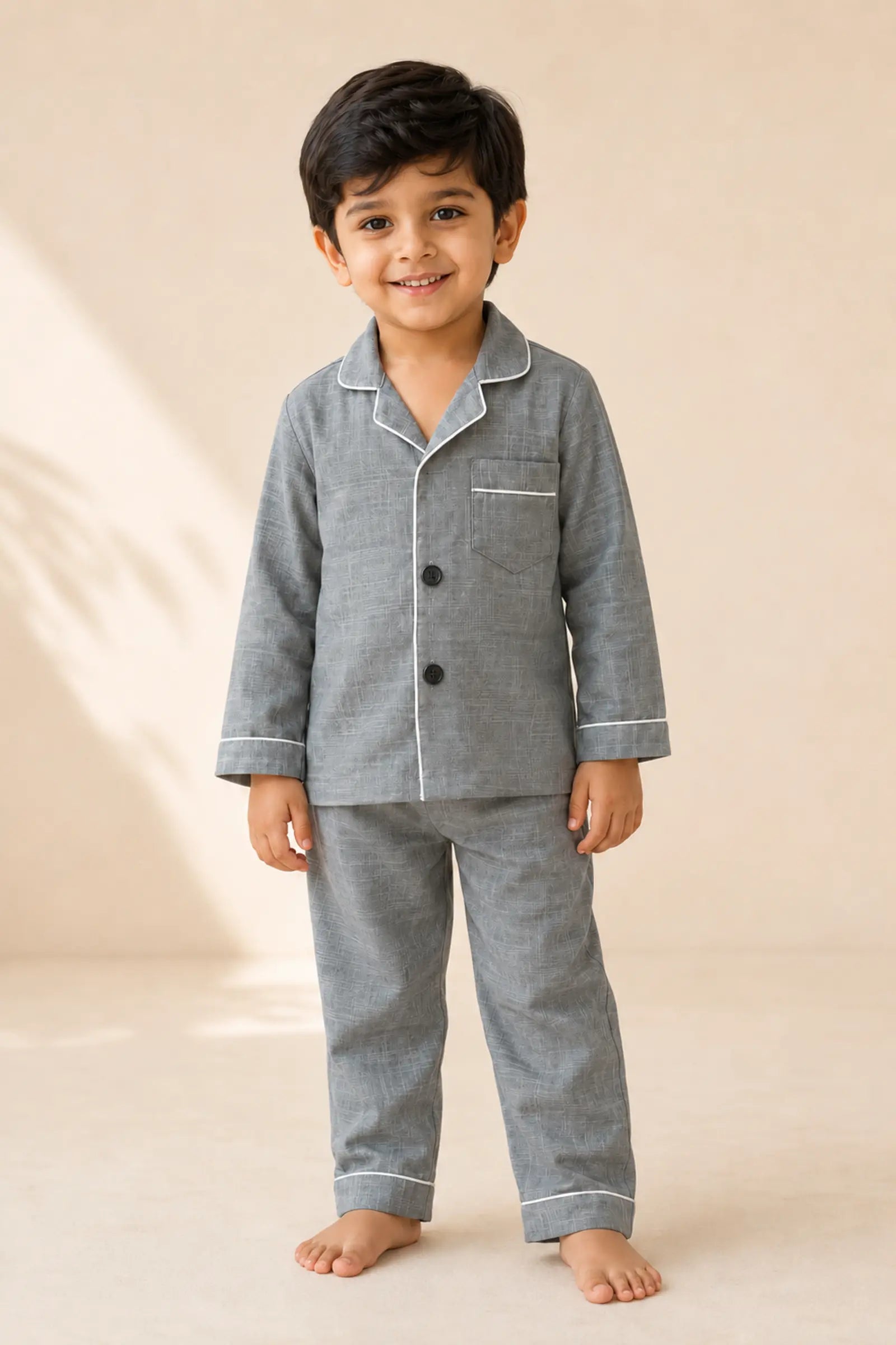 Boy wearing grey white-piped kids night suit, front view