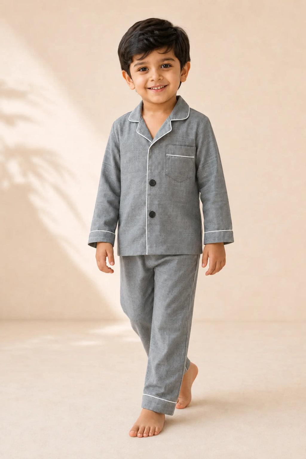 Boy wearing grey white-piped kids night suit in movement