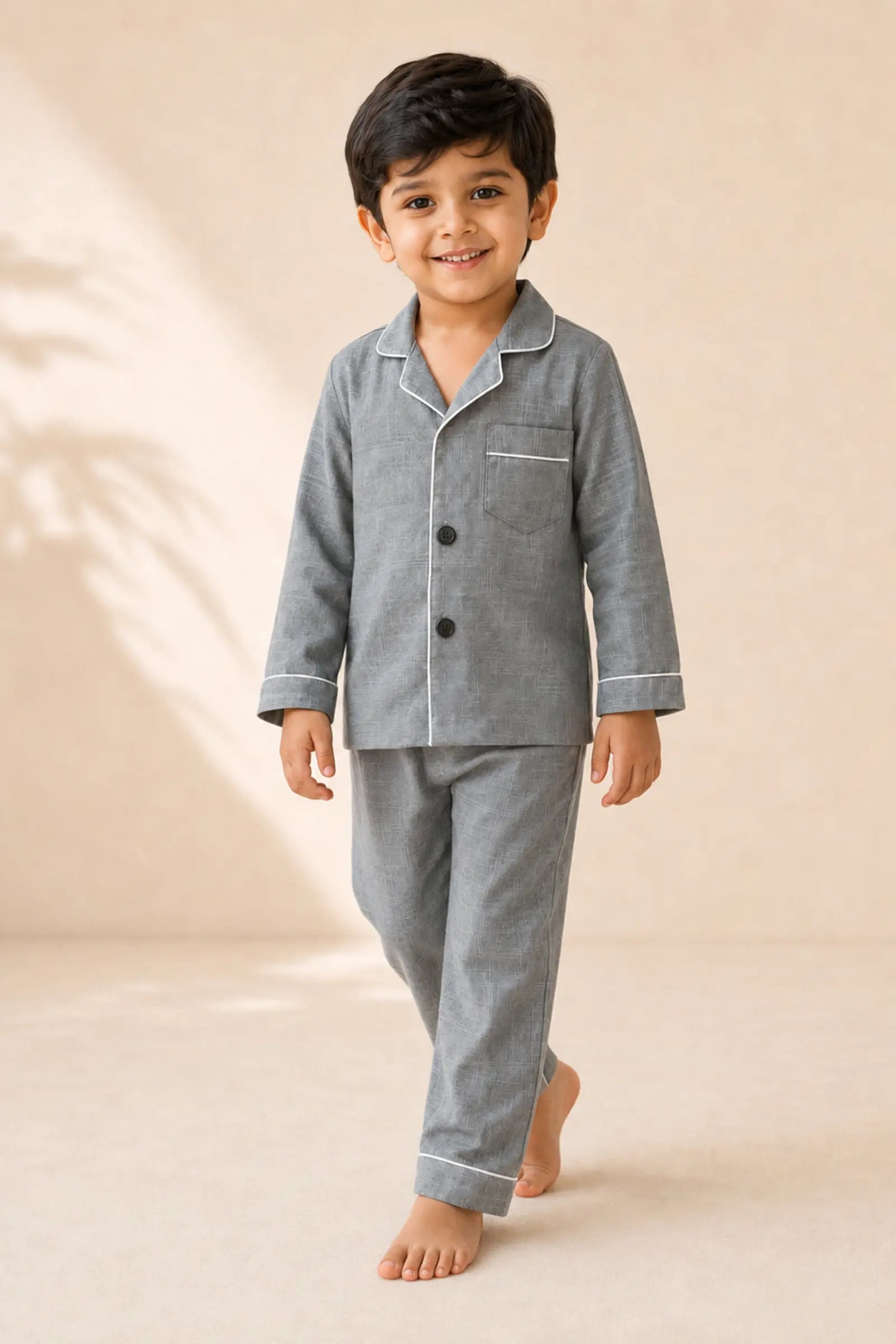 Boy wearing grey white-piped kids night suit in movement