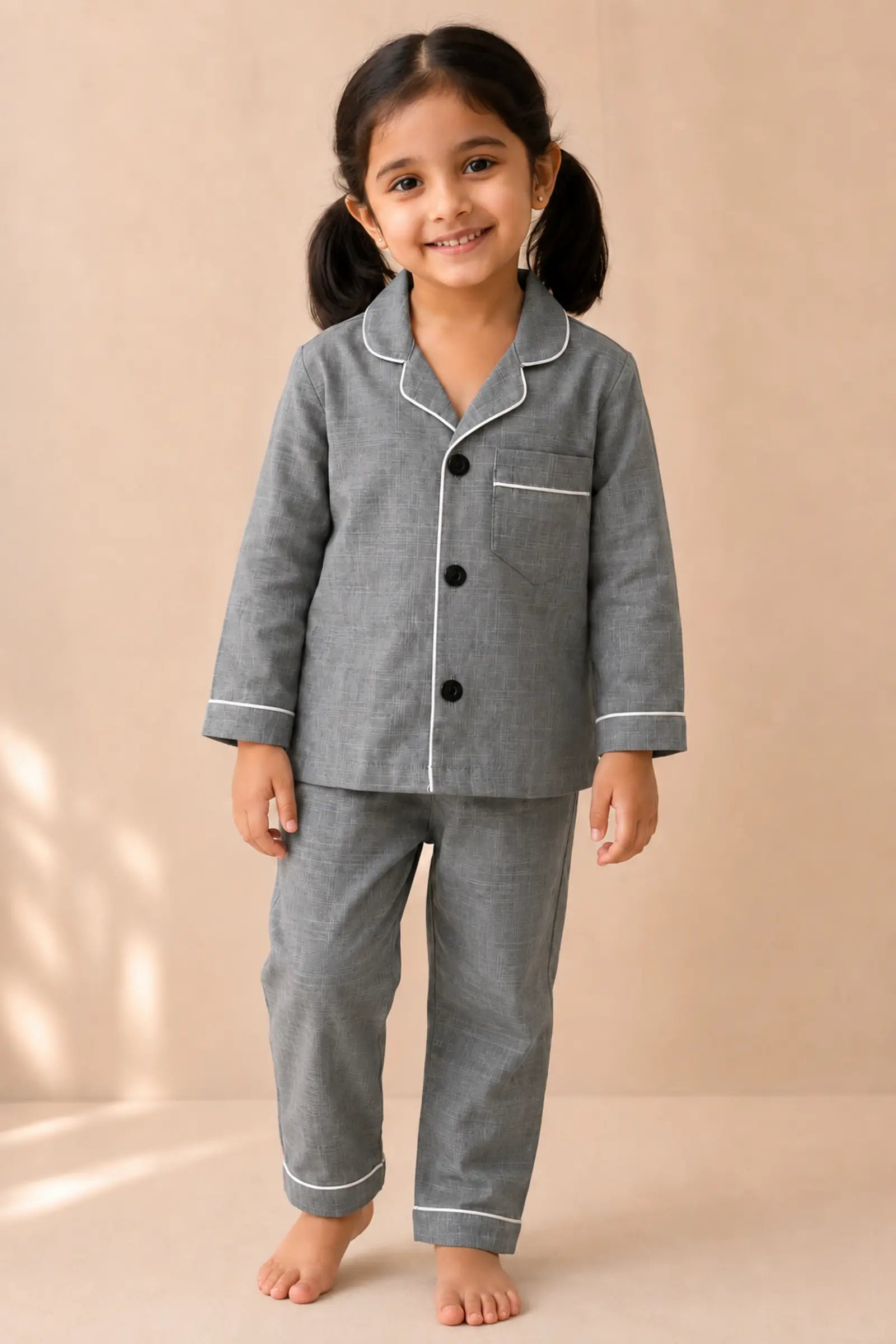 Girl wearing grey white-piped kids night suit, front view