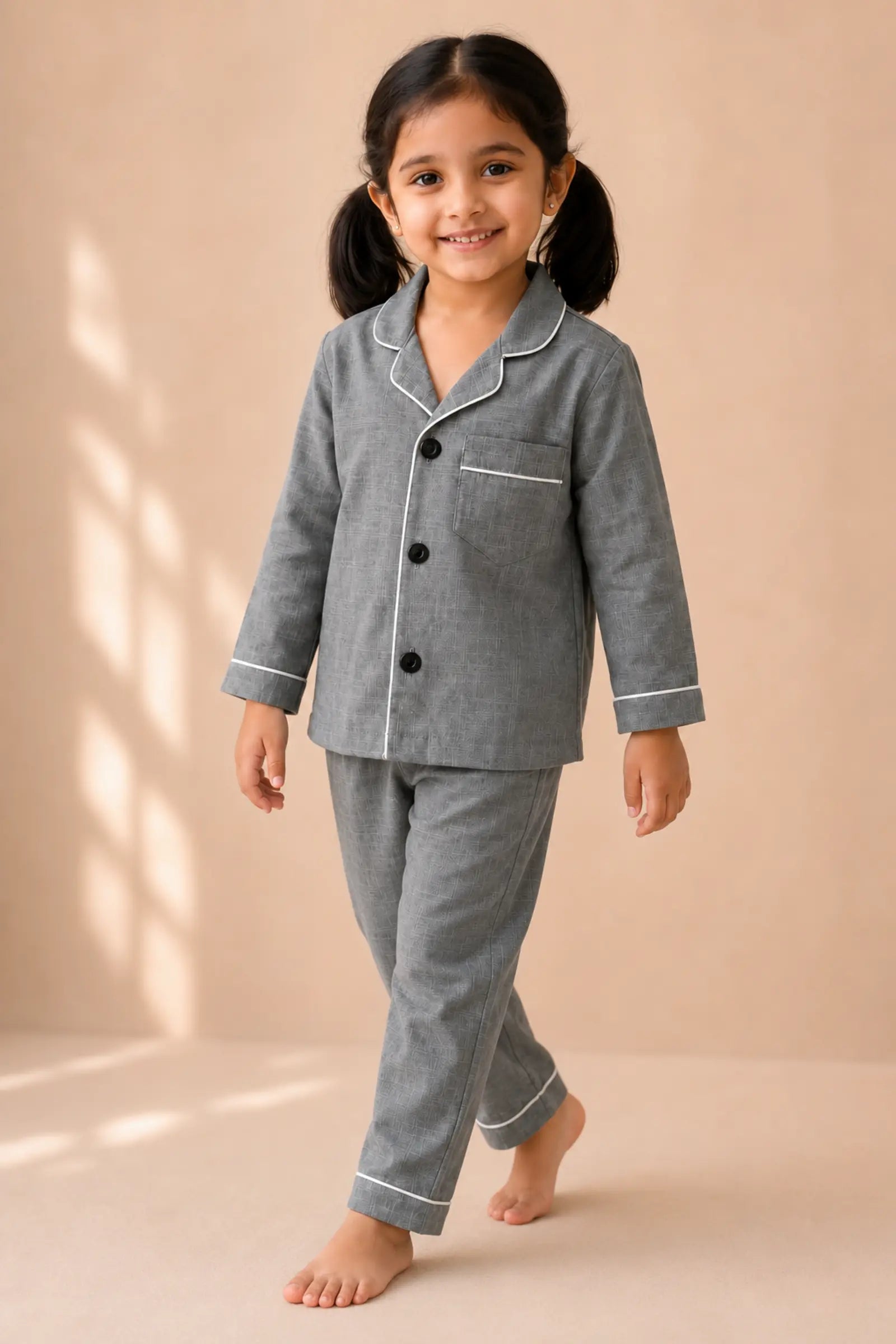 Girl wearing grey white-piped kids night suit in movement