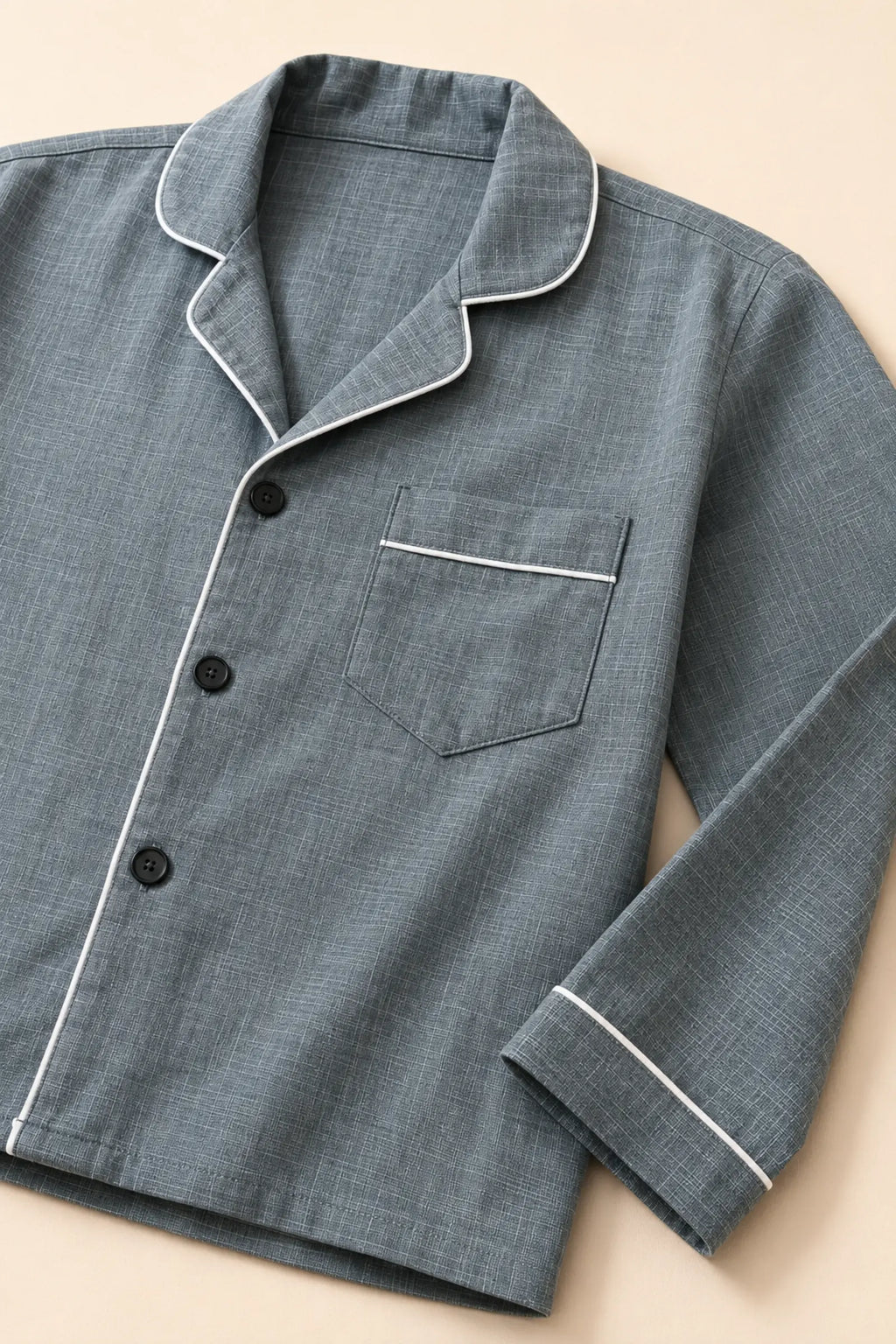 Close-up of white piping, black buttons and chest pocket on grey night suit