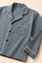 Close-up of white piping, black buttons and chest pocket on grey night suit
