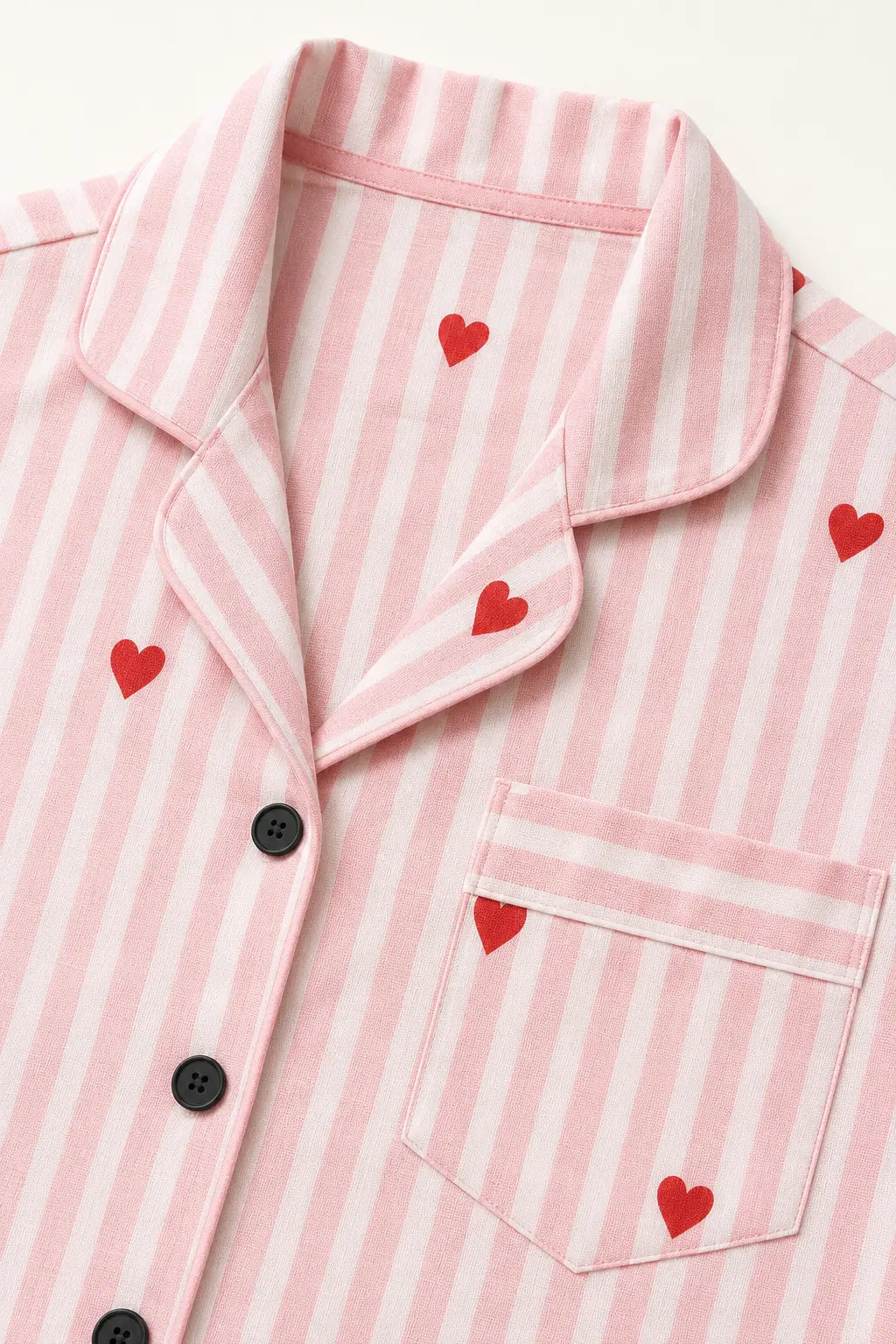 Close-up of pink stripes, red heart print, black buttons and chest pocket