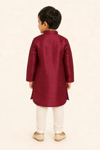 Back view of boy in ruby red kurta and classic white pants