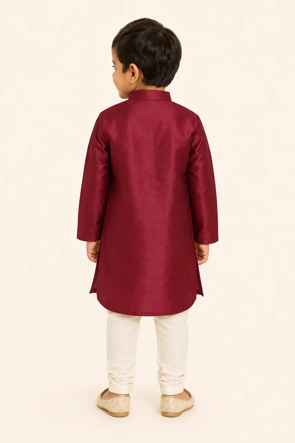 Back view of boy in ruby red kurta and classic white pants